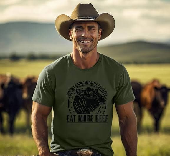 A rancher in a cowboy hat wearing a Support American Cattle Ranchers, Eat More Beef shirt, with his herd grazing behind him